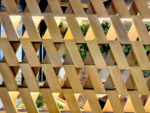 Close up of screen partition or divider in slanted parallelogram shape made by natural wood material. Polygonal tilted shape with repetition. Interior design decoration. Seamless background texture.