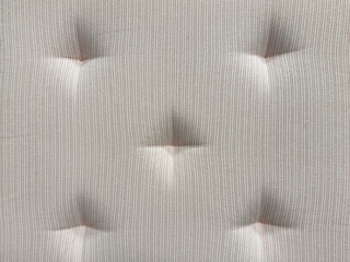 Fototapeta premium Close up of white stripes fabric with recessed embossed button. Suitable for sofa cushion backing, padded, and upholstered panel. Seamless background texture.
