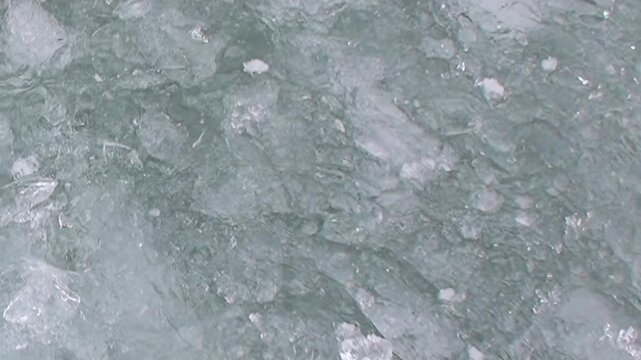 Polar vessel carves path through Arctic Ocean, showcasing fractured ice and churning, emerald waters. This close perspective captures majestic, chilling beauty of frozen northern realm.