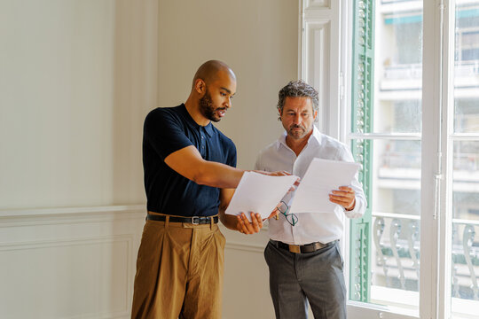 Professionals discussing documents in empty apartment