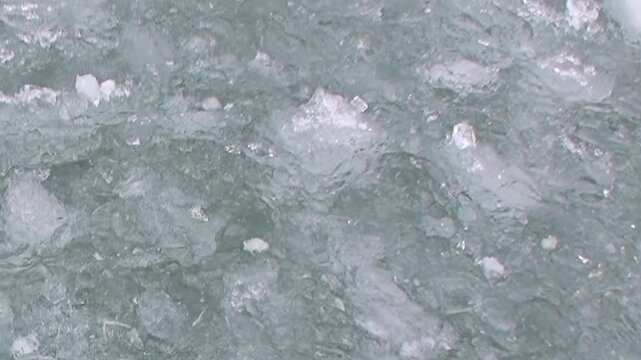 Witness the vast Arctic Ocean from a ship, as brilliant ice chunks and frozen slush swirl in the cold, deep waters. A mesmerizing natural spectacle of the polar world.