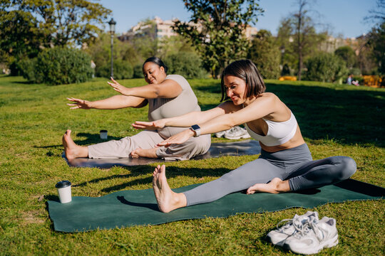Two women practice yoga in a city park