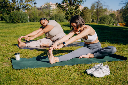 Two women practice yoga in a city park