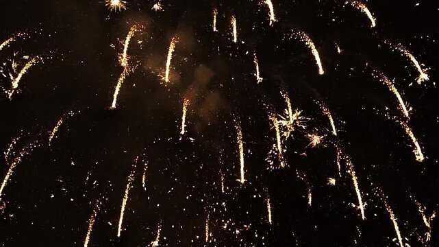 Vibrant golden fireworks exploding in the night sky with bright streaks and sparks