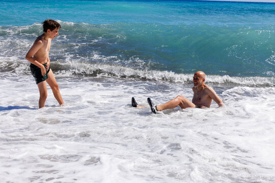 A boy and his father are playing in the waves