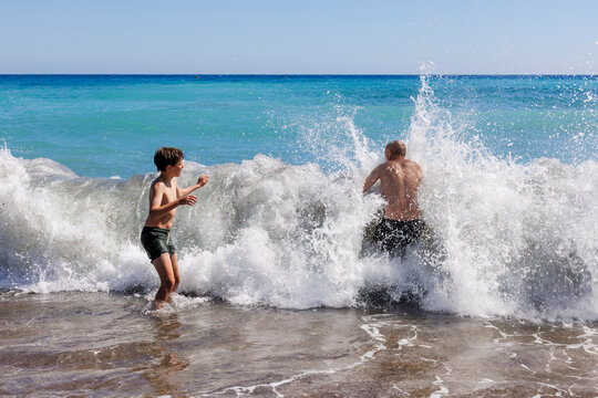 A boy and his father are playing in the waves