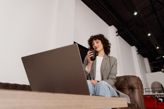 Young Woman Enjoys Coffee While Working on Laptop 