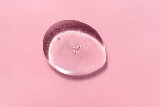 Transparent pink cosmetic serum texture with bubble on pink background