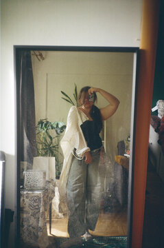 woman takes selfie in mirror while relaxing at home in casual outfit