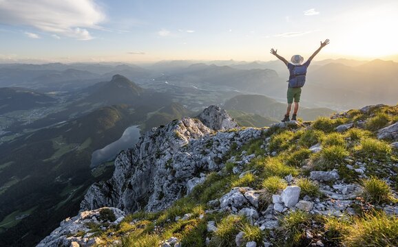 Mountaineer stretching his arms in the air, at the summit of the Scheffauer in the atmospheric evening light, view of Hintersteiner See and Inntal, Kaisergebirge, Wilder Kaiser, Kitzb&uuml;hler Alpen, Tyrol, Austria