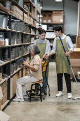 Fototapeta premium A senior woman entrepreneur and her young team pointing out a product on the shelf during a walkthrough in a handmade goods storeroom. Capturing modern small business owners at work.