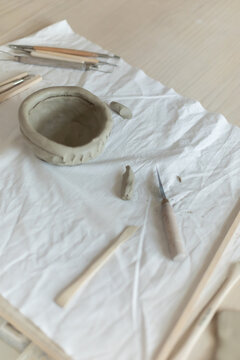 Creative clay pot on worktable with wooden handles and cloth, top-down
