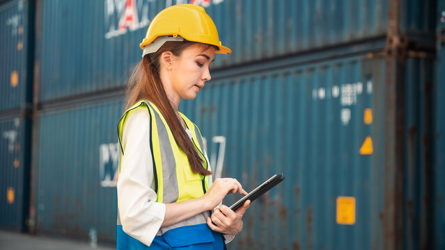Young female engineer logistics worker safety helmet high visibility vest cargo container shipping yard clipboard thinking planning supply chain Woman engineer logistics worker safety helmet high