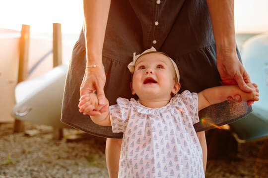 baby girl holding mom's hands, looking up