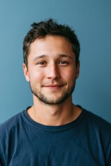 Fototapeta premium Friendly young man smiling portrait with muted blue background for professional headshot and website profile image