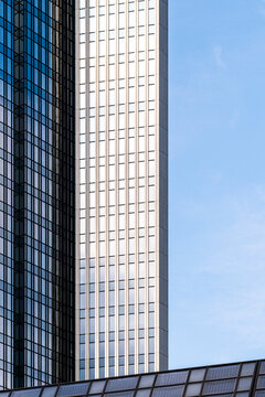 A modern office facade defines commercial architecture on an urban corporate building exterior, where windows rise in a slim tower against open blue sky