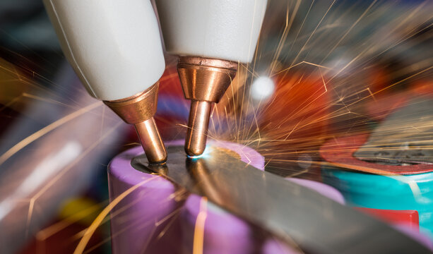 Spot welding nickel strap to lithium-ion cells at battery assembling. Closeup of copper electrodes, flash and sparkling of electric arc with flying sparks at accumulator packs rebuilding. Green power.