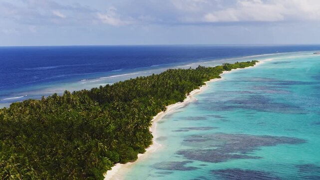 Aerial view of Dhigurah Island, Maldives, long atoll with coconut palms, white sand, turquoise lagoon, coral reefs, gentle waves, small boats, bright daytime light