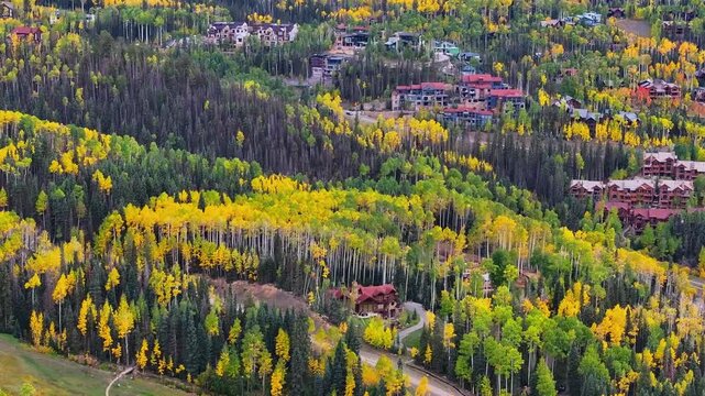 Aerial view of condos and homes in ski mountain town of Telluride, Colorado landscapes with fall foliage trees during autumn season colors in San Juan Mountains - 4K Drone
