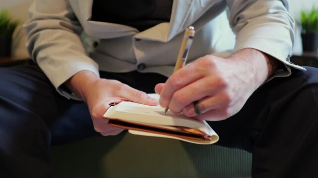 Middle aged candidate anxiously reviews handwritten notes in a leather notebook while waiting for a corporate business job interview in stale office