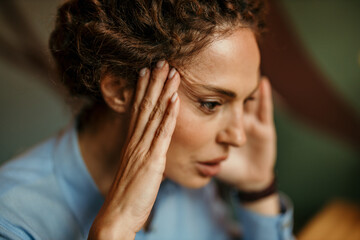 Fototapeta premium Woman experiencing stress and headache with hands on temples