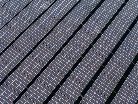 Aerial view of the PLTS 1MWp Bangli solar power plant, featuring rows of photovoltaic panels arranged in a grid pattern in Bangli, Bali, Indonesia.