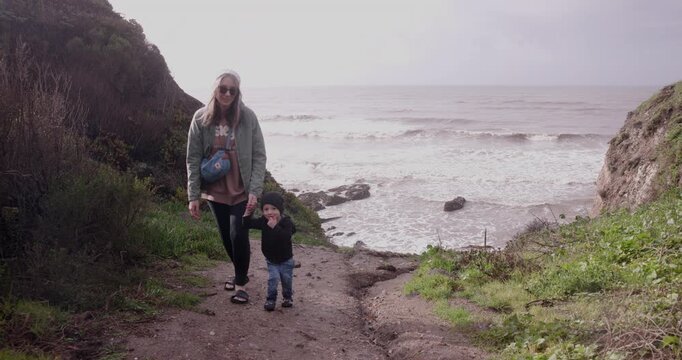 Mother and Toddler Son Walking Hand in Hand Up Sandy Hill at Pismo Beach, California