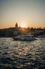Naklejka premium Sunset Over the City With Boats Anchored Along the Waterfront Near Shoreline Buildings in Istanbul