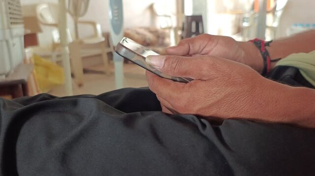 Extreme close up of man hands holding and typing on a smartphone screen indoors