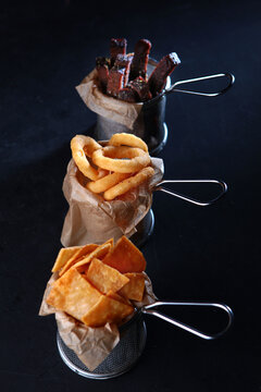 Beer snacks. An assortment of beer snacks. Brown bread croutons, squid rings and homemade chips on wooden board