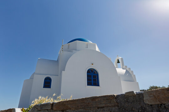 Traditional white and blue Greek chapel or church on Antiparos island in Greece under a clear blue sky on a sunny day.