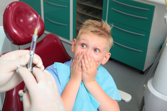 Childhood fear of injection. Little boy experiences fear at dentist appointment. Fear of dentist. Child covered his mouth with his hands