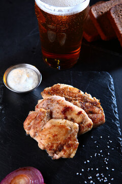 Fresh grilled chicken fillet with spices on dark background. Dish cooked on fire. Beer in tall glass. An appetizer for beer or an independent dish