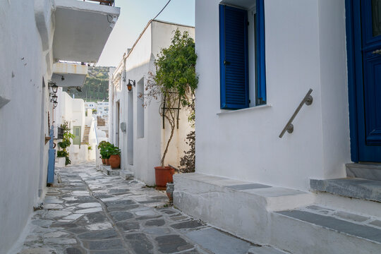 Traditional white Greek residential buildings and houses with blue doors and windows in the village of Lefkes on Paros island in Greece on a sunny day.