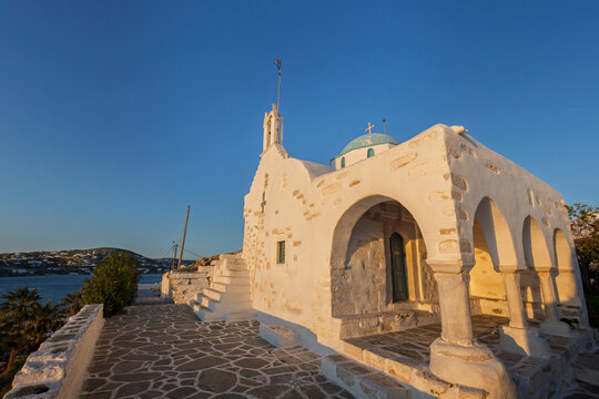 Traditional Agios Konstantinos (Saint Constantine) church painted in white in Paroikia (Parikia) town on Paros island in Greece under a clear blue sky on a sunny evening.