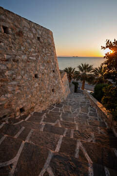 Old stone wall and seascape in Paroikia (Parikia) town on Paros island in Greece at sunset.