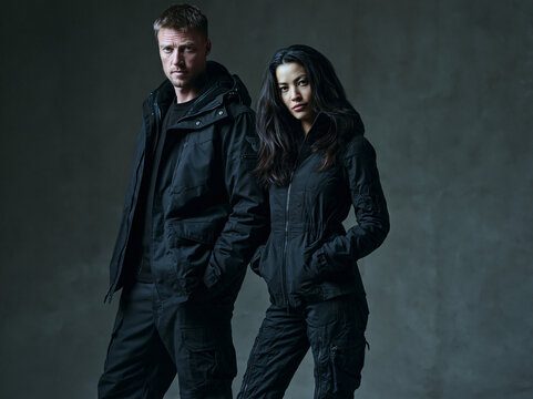 Two People in Black Tactical Gear Standing Together