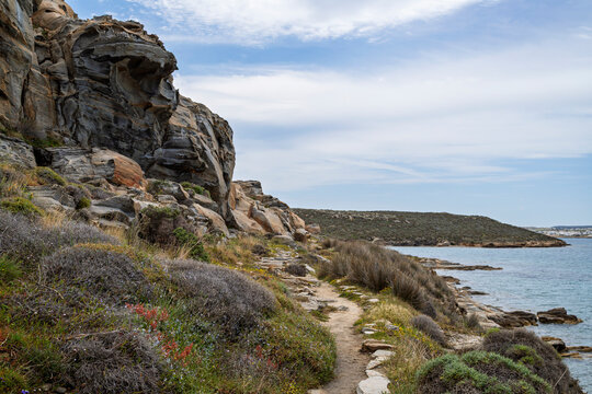 View of peculiar cliff and rocky, hilly and lush coastline by the Aegean Sea at the Paros Park on Paros island in Greece on a sunny day.