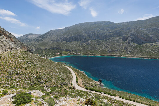 Rocky, lush and mountainous landscape and the Aegean Sea at the Arginonta Bay on Kalymnos island in Greece on a sunny day.