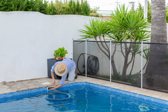 Pool maintenance worker cleaning swimming pool filter by hand
