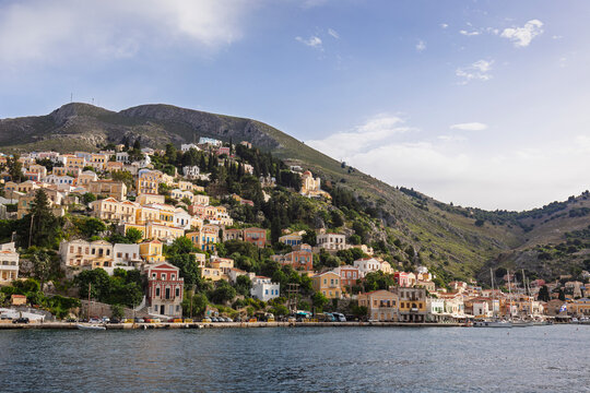 Colorful buildings on a hillside in the idyllic town of Symi by the Aegean Sea on Symi (Simi, Syme) island in Greece on a sunny day.