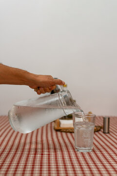 Close up of hand pouring cold water into glass during summer heatwave