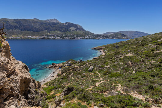 Rugged and lush landscape, beaches, coastline and the Aegean Sea on Telendos island in Greece on a sunny day. Mountainous Kalymnos island is in the background.