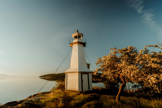 Minimalist Swedish lighthouse against golden hour sky, Lake Vattern, Sweden.