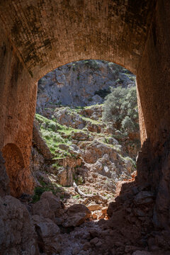 Old bridge near the ruins of the Katholiko monastery along the Avlaki Gorge hiking train in Crete, Greece. Viewed from below on a sunny day.
