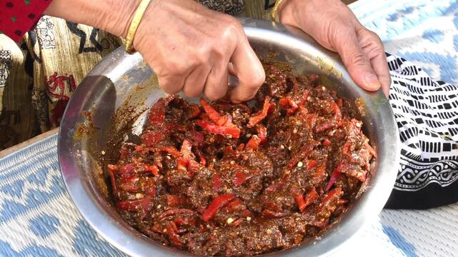 mixing homemade achar outside in winter sun. 