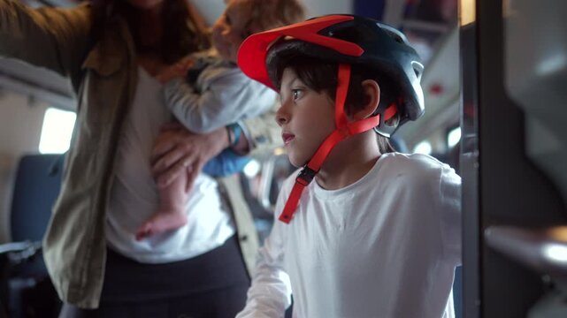 Boy waiting with kick scooter inside passenger train before disembarking with family, highlighting childhood independence, sustainable mobility and everyday public transportation
