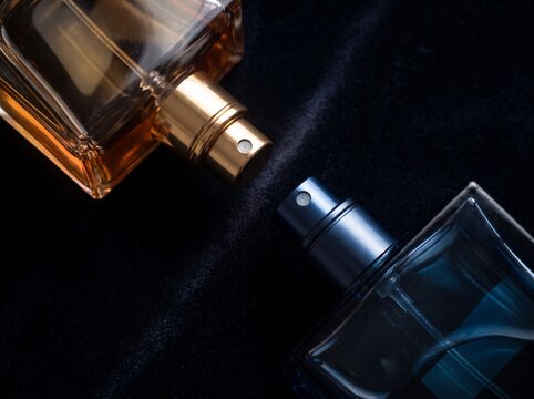 Two luxury glass perfume spray bottles on black velvet background with fragrance