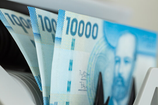 Chilean Peso banknotes stacked together inside currency counting machine. Chile financial market, South American economy, business background and monetary concept