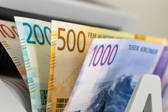 Norwegian Krone banknotes stacked together inside currency counting machine. Norway financial market, scandinavian economy, business background and monetary concept